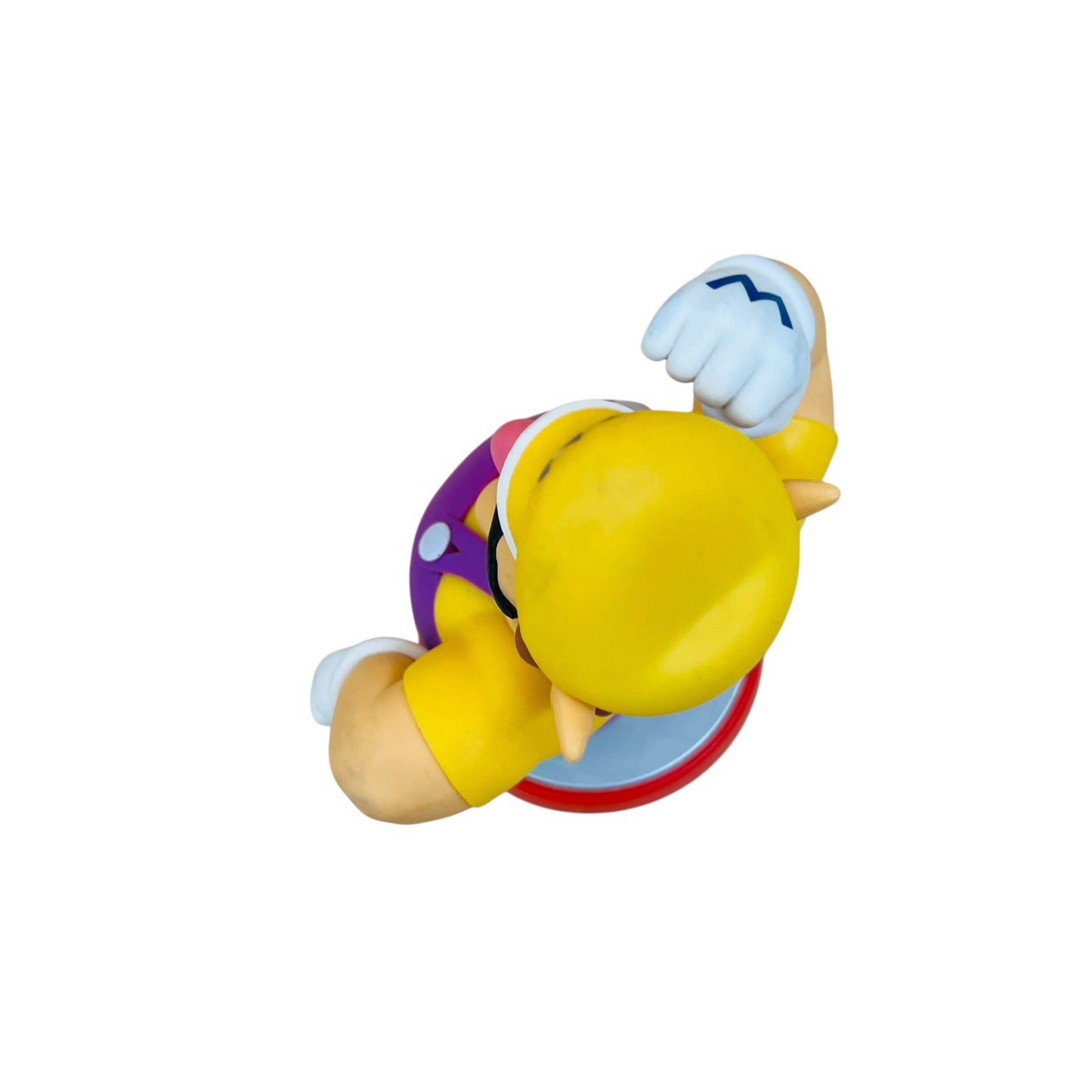 Toy figure of a character with a yellow hat and purple outfit on a white background