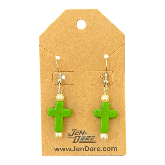 Green cross-shaped earrings with pearl-like beads on a JenDore branded card.