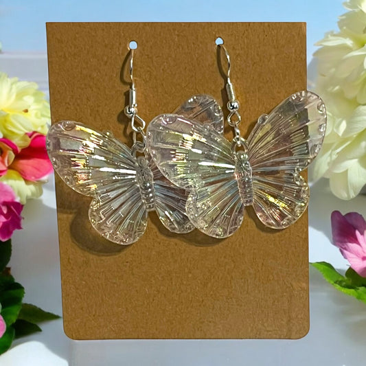 Butterfly-shaped earrings on a brown card with flowers in the background