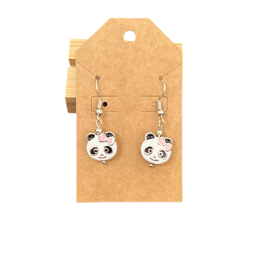 Close-up of JenDore handmade metal panda dangle earrings with pink bow detail and playful, lightweight design.