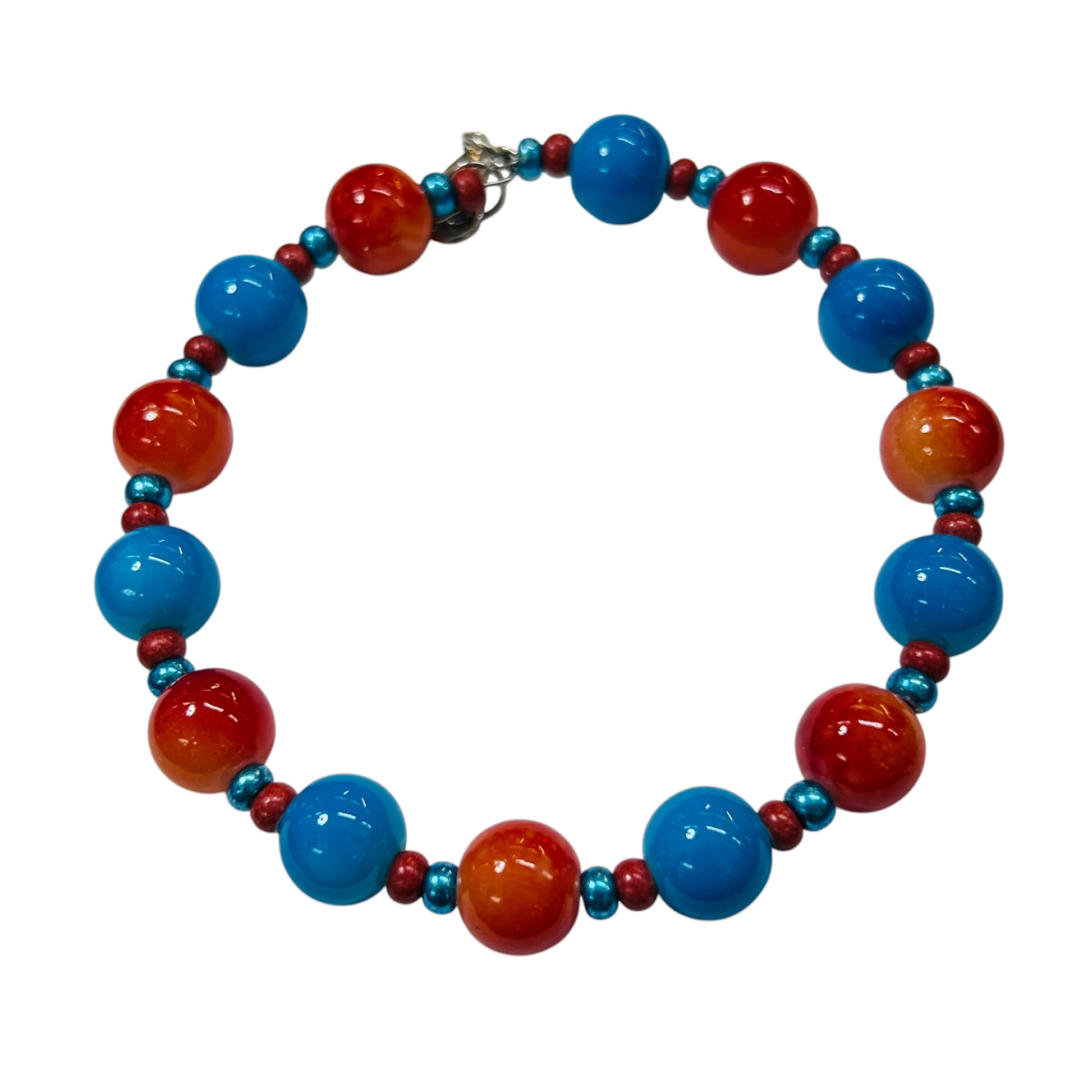 A beaded bracelet featuring alternating large glossy red-orange and blue beads, with smaller metallic teal and red spacer beads, and a small silver clasp, shown on a plain white background.