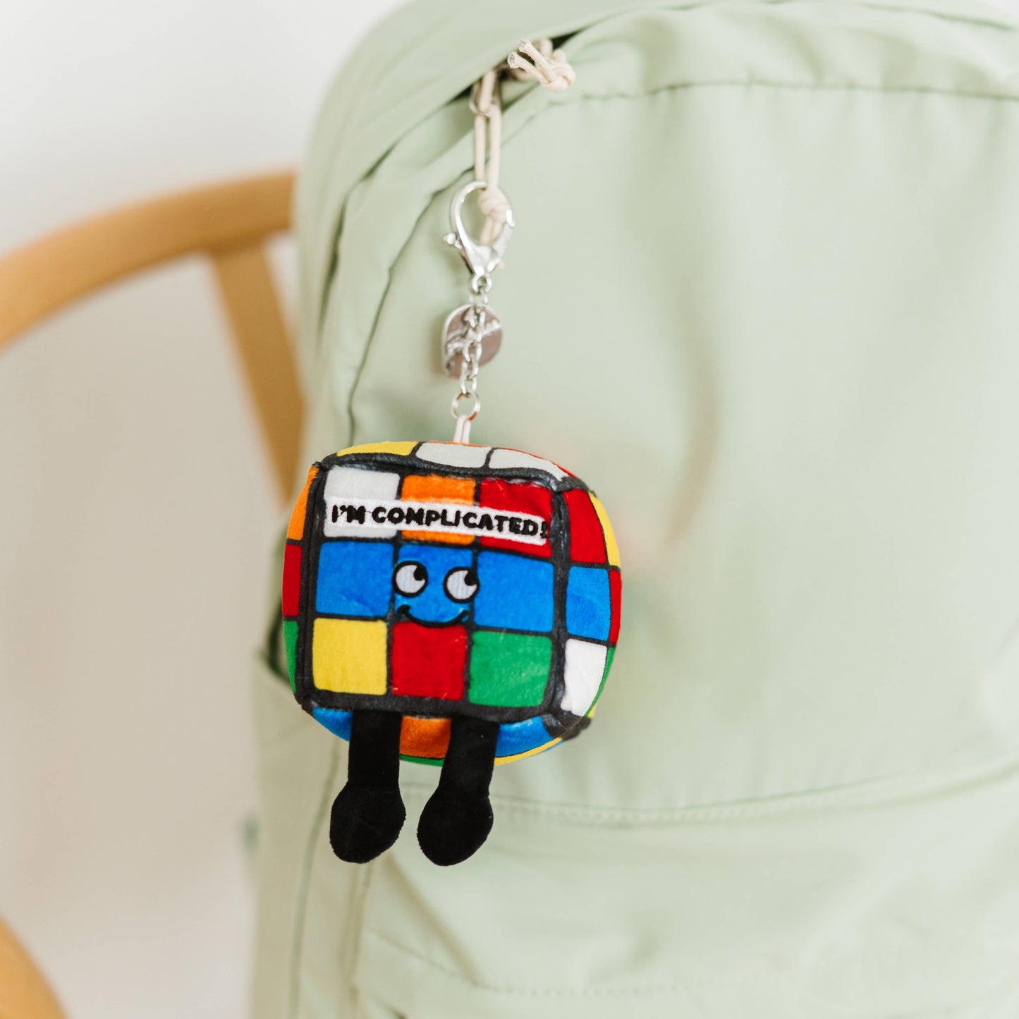 Colorful keychain with a character and 'I'm Complicated' text attached to a green bag.